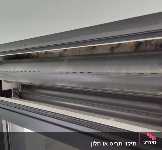 תריס גלילה מתכת חשוף בתוך מסגרת חלון